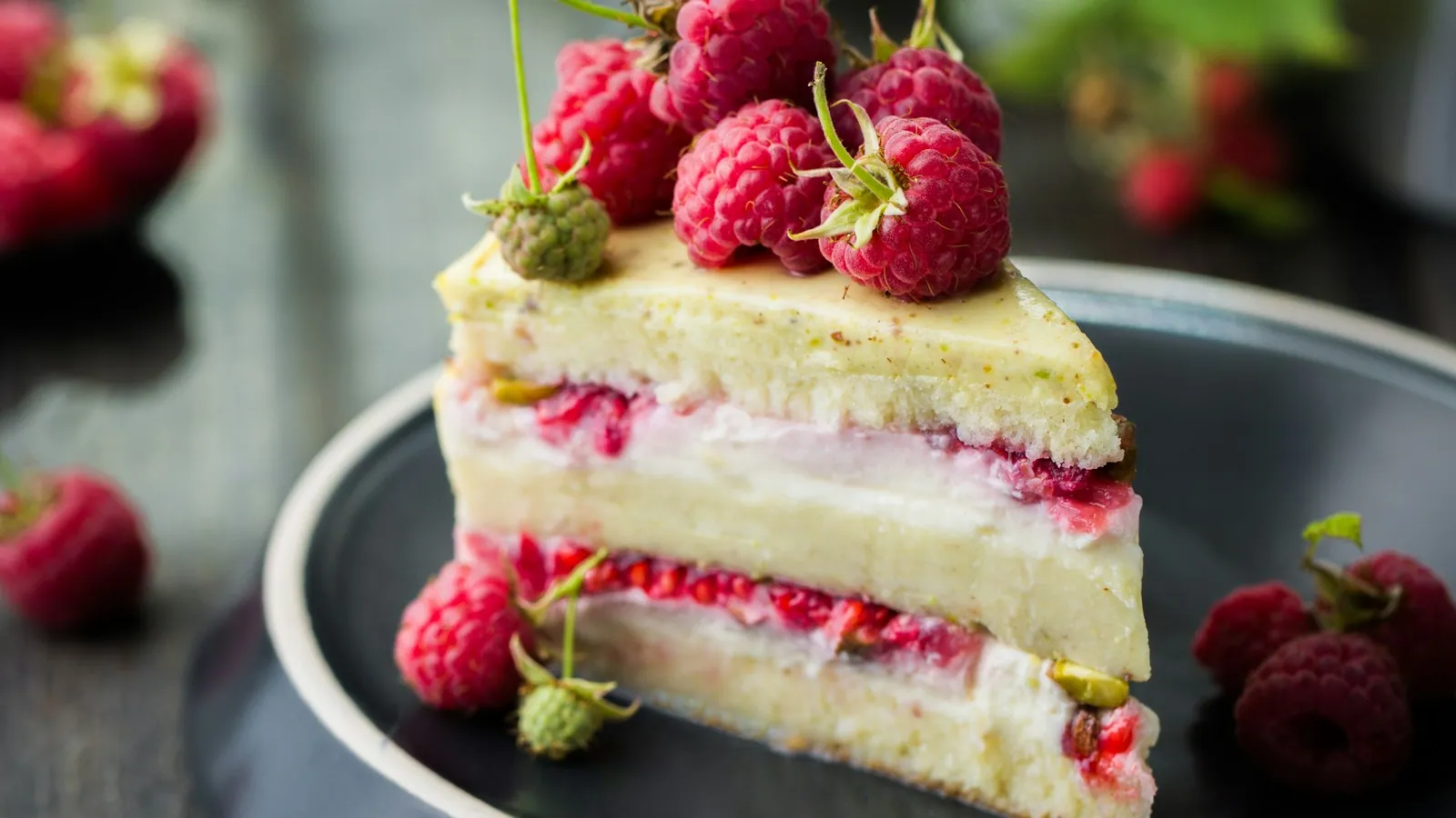 Porción de torta con crema y frambuesas.